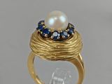 a close up of a gold ring with a pearl and blue sapphires