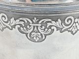 a close up of a silver vase with a handle on it