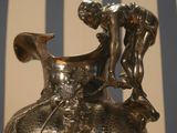 a silver vase with a little boy on top of it