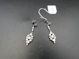 a pair of earrings with white stones on a black surface