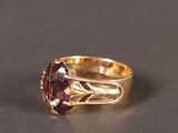 Gros plan sur une bague en or ornée d'une pierre violette.
