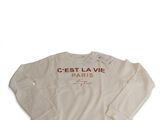 Le t-shirt à manches longues est blanc, avec une inscription en rouge.