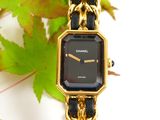 an image of a black and gold watch sitting on top of a leaf