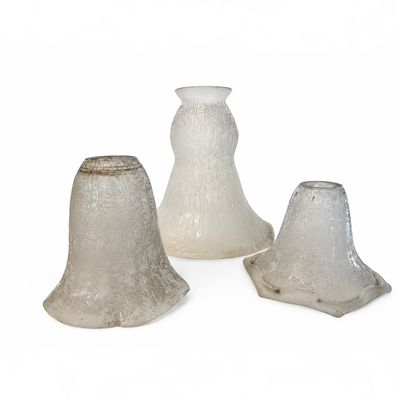 trois vases en verre posés l'un à côté de l'autre sur une surface blanche