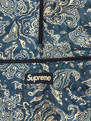 a blue and white paisley print jacket with black zippers