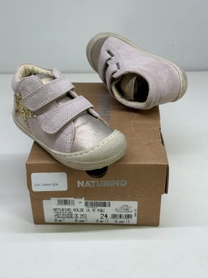des chaussures de petite fille dans une boîte posée sur une surface blanche