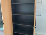 tall wooden bookcase with black shelves in an empty room