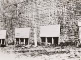 a black and white photo of a group of people standing in front of a brick wall