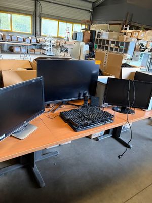 deux écrans et un clavier posés sur un bureau dans un entrepôt