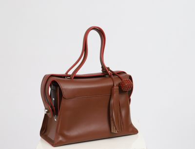 a brown handbag sitting on top of a white table