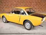 a yellow car that is parked in front of a brick wall