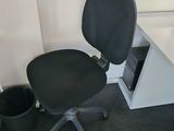 a black office chair sitting in front of a white desk