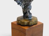 statue d'un aigle posée sur un socle en bois, sur fond blanc
