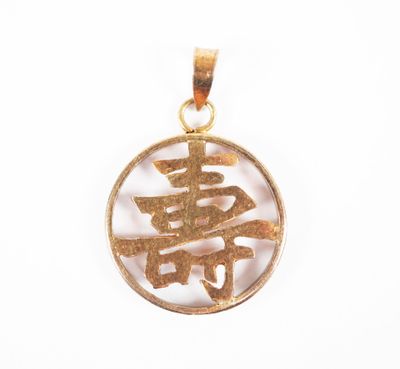 un gros plan d'un pendentif plaqué or orné d'un symbole chinois