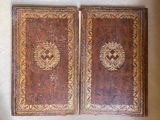 pair of antique leather bound books with gold and brown designs