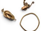 two pieces of gold jewelry on a white surface