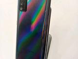 a close up of the back of a black phone with a rainbow background