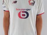 Cet homme porte une chemise blanche sur laquelle figure un numéro 6 rouge et bleu.
