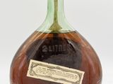an old bottle of liquor sitting on top of a white surface