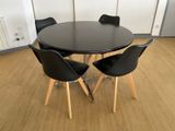 a black table with four chairs around it in a room
