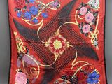 a red silk scarf with flowers and feathers hanging on a clothes line