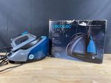 a blue and black steam iron sitting on top of a wooden table
