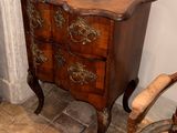 a small chest of drawers next to a chair in a room