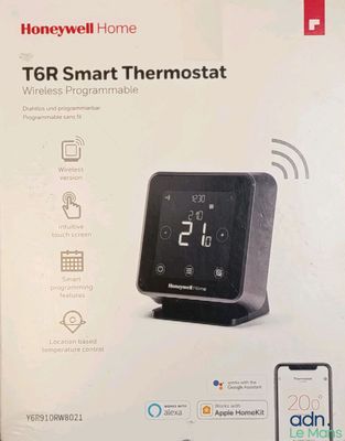 emballage d'un thermostat intelligent noir sur lequel est posé un téléphone