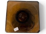 a brown vase sitting on a white surface with a tag on it
