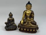 deux statues de bouddhas assis l'une à côté de l'autre sur une table