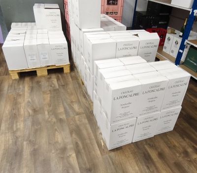 Plusieurs piles de cartons sont empilées sur une palette dans un entrepôt