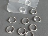 beaucoup de bagues en argent posées sur une table à côté d'un sac