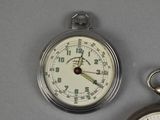 a silver pocket watch sitting next to a silver pocket watch