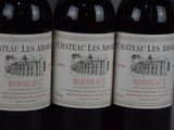 three bottles of red wine are lined up on a table