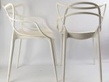 two white chairs sitting next to each other on a white surface