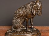 a bronze statue of a dog sitting on top of a wooden table