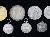 six médailles d'argent et d'or de différentes tailles sur fond noir