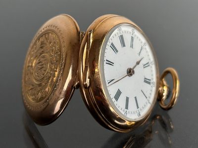 a gold pocket watch with roman numerals on it