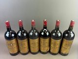 six bottles of wine are lined up in a row on a table