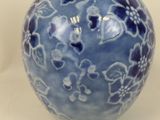 a blue vase with flowers on it sitting on a table