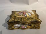 une boîte dorée ornée d'une peinture sur un fond blanc