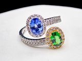 two rings with different colored stones on top of a white surface