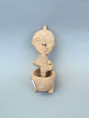 une image représentant une figurine en argile représentant une personne assise dans un pot