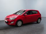 La voiture rouge est garée dans une pièce blanche au sol noir.
