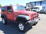 a red jeep parked in a parking lot with other vehicles in the background