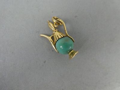 un gros plan d'un pendentif plaqué or orné d'une pierre verte