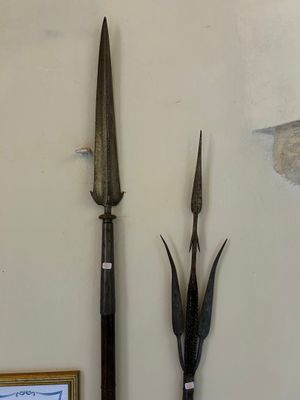 une photo représentant un mur sur lequel sont accrochés une image représentant une lance et un tableau encadré
