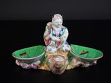 une figurine représentant une personne assise sur un bol