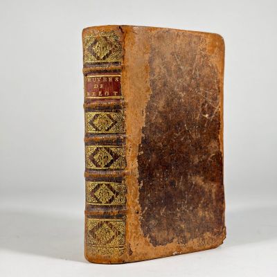 an old book sitting on top of a white table next to a white wall