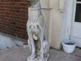 une statue représentant un chien assis sur le trottoir